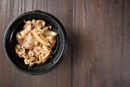 Gyudon in a white round bowl on a wooden tableの写真素材