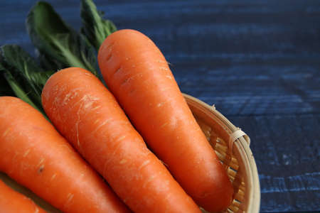Orange carrot in a colander on a blue tableの写真素材