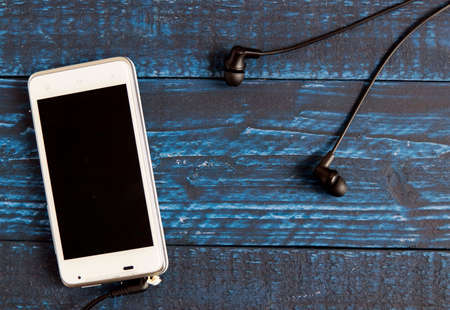 Smartphone and wired earphones on the blue tableの写真素材