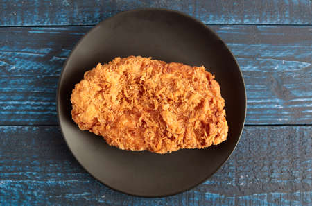 High-calorie pork cutlet fried in oil on a blue tableの写真素材