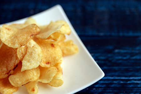 Potato chips on a blue table with a lot of calories called mild dragの写真素材