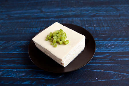 Tofu sprinkled with small green on the tableの写真素材