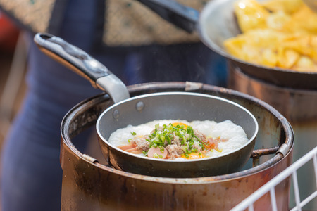 Frying sausages and scrambled eggs in fatの写真素材