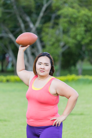 Beautiful fat woman playing american football in the park.の写真素材