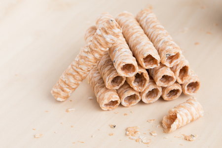 Crispy rolled wafer sticks, traditional dessert in Thailand, are collocated on the wood board.の写真素材