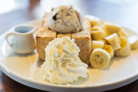 Close Up on, Honey Toast, Bread Buttered Toast, Banana, Ice Cream and Whipped Cream Dessert on a white Dishの写真素材