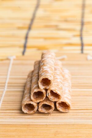 Crispy rolled wafer sticks, traditional dessert in Thailand, are collocated on the wood board.の写真素材