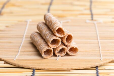 Crispy rolled wafer sticks, traditional dessert in Thailand, are collocated on the wood board.の写真素材