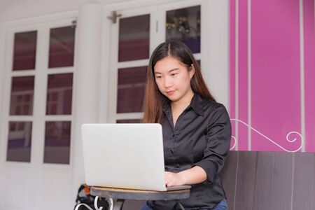 Beautiful businesswoman working on her laptop while sitting in coffee shop in a town.の写真素材