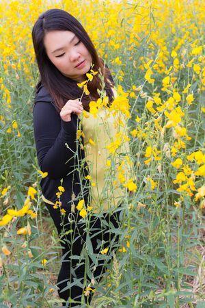 Portrait of beautiful fat woman touching and smelling sunn hemp happily in the flower gardenの写真素材