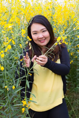 Portrait of beautiful happy fat woman touching sunn hemp happily in the flower gardenの写真素材