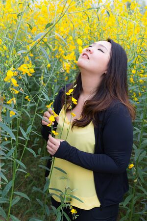 Portrait of beautiful fat woman touching and smelling sunn hemp happily in the flower gardenの写真素材