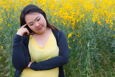 portrait of happy beautiful fat woman posing as thinking in sunn hemp garden.の写真素材
