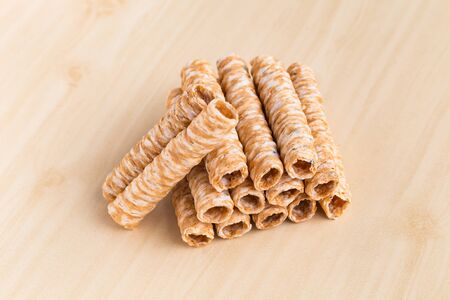 Crispy rolled wafer sticks, traditional dessert in Thailand, are collocated on the wood board.の写真素材