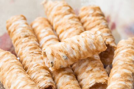 Crispy rolled wafer sticks, traditional dessert in Thailand, are collocated on the wood board.の写真素材