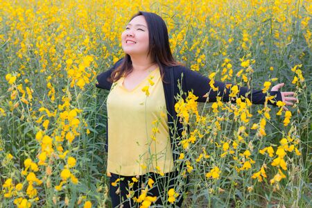 portrait of happy beautiful happy fat woman breathing fresh air and enjoying smell in sunn hemp garden.の写真素材