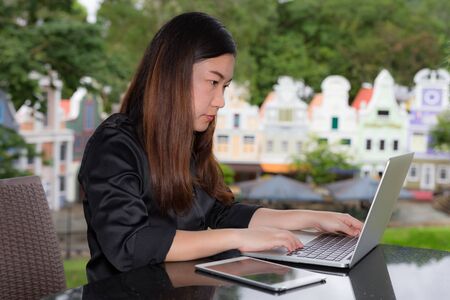Beautiful businesswoman working on her laptop and tablet while sitting in coffee shop in a town.の写真素材