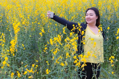 portrait of happy beautiful fat woman taking selfie in sunn hemp garden.の写真素材