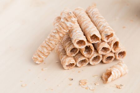Crispy rolled wafer sticks, traditional dessert in Thailand, are collocated on the wood board.の写真素材