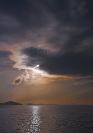 sunset over the sea with clouds and mountains in the background.の写真素材