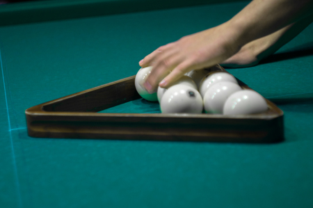 billiard green table in hall with white balls with man handの写真素材