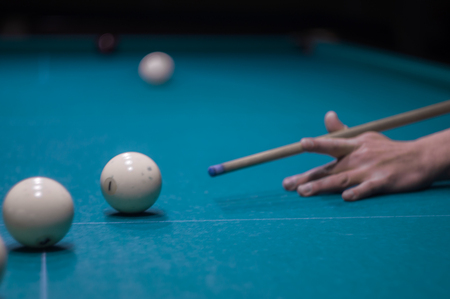 billiard green table in hall with white balls with man handの写真素材