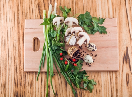 Halves of mushrooms spices and herbs on a cutting boardの写真素材