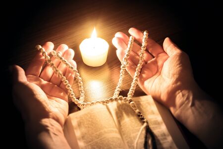 Praying hands, Islamic background. The holy Koran under candlelight. Book in candlelight