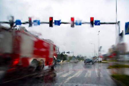 Fire truck. Go to the red light of the traffic light. Rainy day