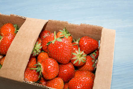 Ripe strawberries are scattered on the table. red berry on a wooden background. packing the product in a boxの写真素材