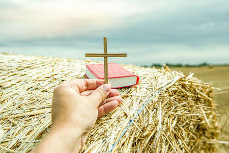 cross of god in hand on countryside background .