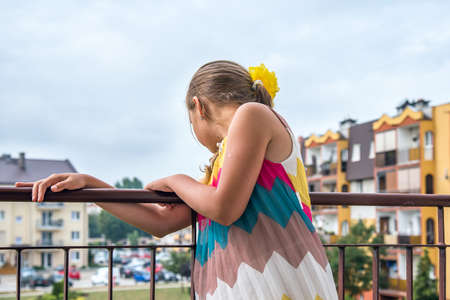 A beautiful girl standing on a balcony and enjoying the morning sun.の写真素材