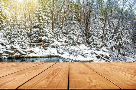 Empty wooden deck table with winter background, trees in the snowの写真素材