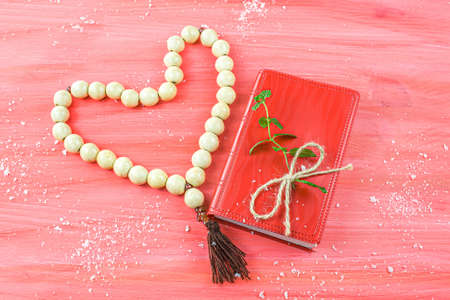 Christmas red background with Bible and rosary on the table, place for promotional text