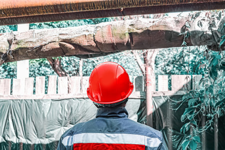 A worker in a red helmet. gray suit with red