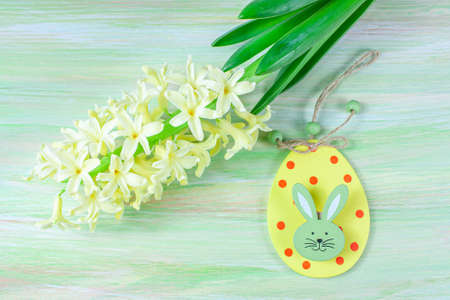 Easter hare on a floral background. Yellow hyacinth on the table.