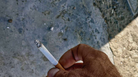 smoldering cigarette in a man's handの写真素材