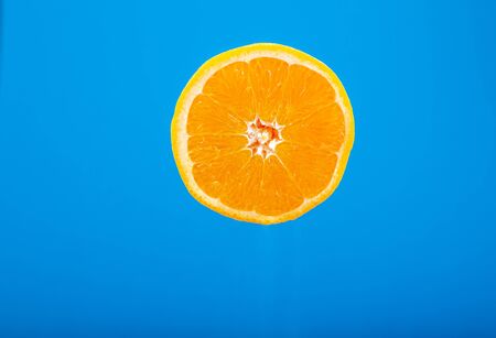 Cut orange. Field fruit. Orange on a blue background. A drop of juice. Wet Orange. Water drops on the fruit skin. Fresh fruit.の写真素材