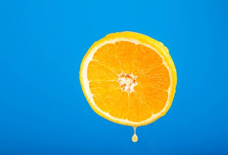 Cut orange. Field fruit. Orange on a blue background. A drop of juice. Wet Orange. Water drops on the fruit skin. Fresh fruit.の写真素材
