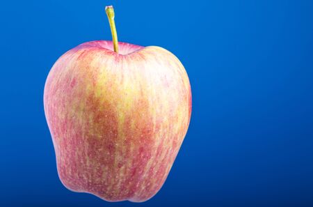 Red apple on a blue background. Fruits on a blue background. Isolated from background. Vegetarian food. Fruit in a slimming diet. Ripe fruit.の写真素材
