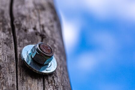 Screw in a wooden board. Fragment of an old building. Wooden construction. Metal screws and nuts.の写真素材