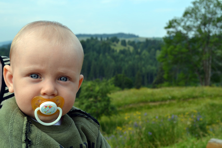 blue-eyed baby with a pacifier outdoorの写真素材