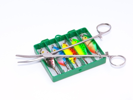A box of colourful and vibrant lures and forceps isolated on a white background