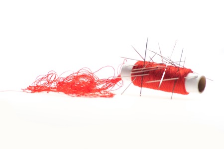 Nice red thread for sewing with different needles in it  Low angle  Isolated on the white backgroundの写真素材