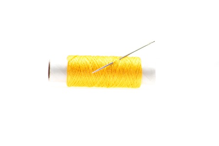 Nice yellow reel of thread for sewing with the needle in it  Isolated on the white backgroundの写真素材