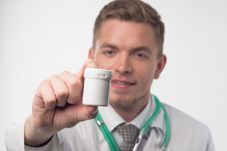 Selected focus on the white drug container in the hand of the doctor, who is on background