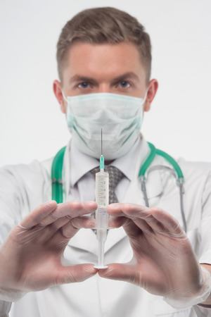 Selected focus on the injector in doctors hands, who is on the backgroundの写真素材