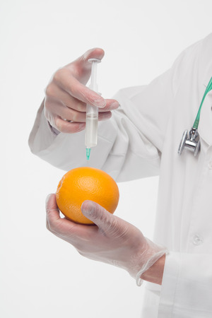 Doctor in expendable gloves, giving an injection the orange  Isolated on the white backgroundの写真素材