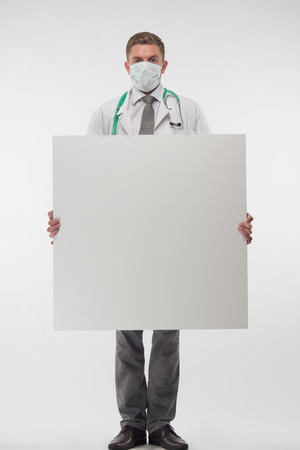 Full length portrait of handsome young doctor in the gauze bandage, holding a big sheet of paper  Isolated on the white backgroundの写真素材