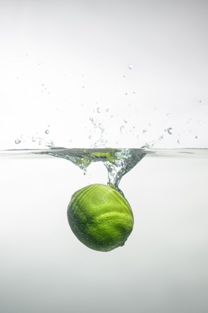 Ripe tempting lime dipped into the water with little air bubblesの写真素材